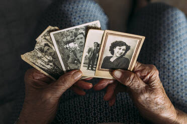 Hände einer Frau halten Fotos aus der Vergangenheit zu Hause - EGHF00777