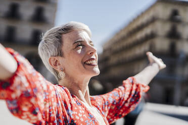 Smiling woman with arms outstretched on sunny day - JCZF01279