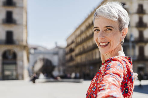 Happy woman taking selfie in city on sunny day - JCZF01281