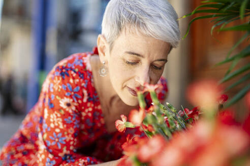 Frau im roten Kleid riecht an Blumen - JCZF01284