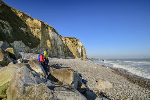 Mature man and woman standing by rocks at coastline - ANSF00571