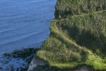 Mature woman walking on green chalk cliffs near sea - ANSF00588