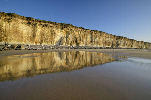 Reflection of chalk cliffs in water puddle at beach - ANSF00597