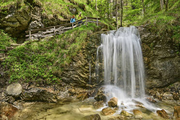 Älterer Mann und Frau betrachten einen Wasserfall im Wald - ANSF00633