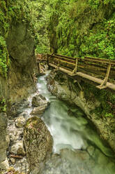 Wooden narrow bridge over water with rocky mountains - ANSF00635