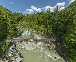 Holzbrücke über den Fluss in den Wäldern der Berchtesgadener Alpen an einem sonnigen Tag - ANSF00645