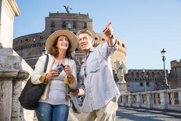 Senior couple at Castel Sant' Angelo, Rome - Happy tourists visiting italian famous landmarks - DMDF04429