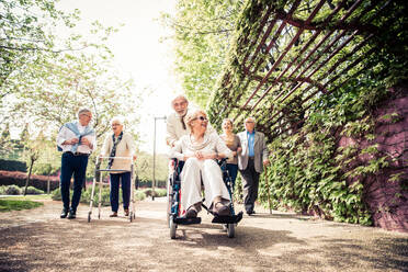 Gruppe älterer Menschen mit einigen Krankheiten, die im Freien spazieren gehen - Ältere Gruppe von Freunden, die Zeit miteinander verbringen - DMDF04440