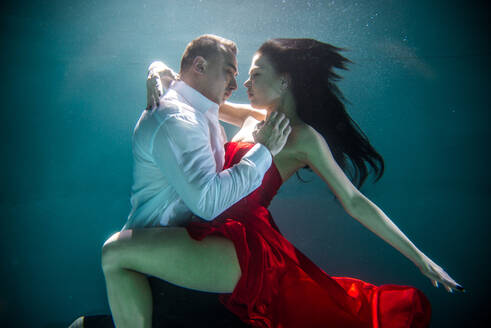 Couple swimming underwater with beautiful dress - Artistic dreamy portrait - DMDF04448