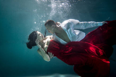 Couple swimming underwater with beautiful dress - Artistic dreamy portrait - DMDF04450