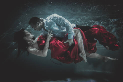 Couple swimming underwater with beautiful dress - Artistic dreamy portrait - DMDF04451