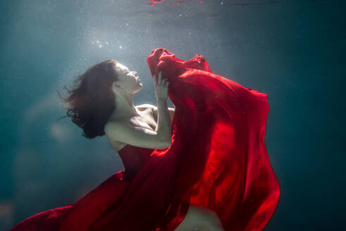 Beautiful woman swimming underwater with elegant dress - DMDF04453