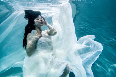 Beautiful woman swimming underwater with elegant dress - DMDF04460