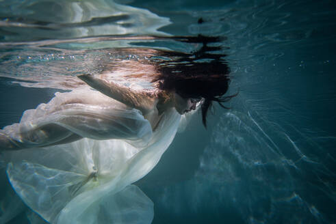 Beautiful woman swimming underwater with elegant dress - DMDF04461