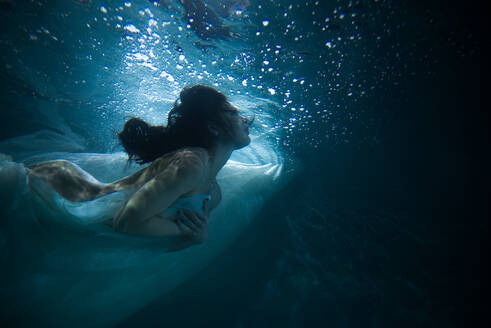 Beautiful woman swimming underwater with elegant dress - DMDF04463