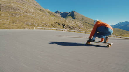 Cinematic downhill longboard session. Young woman skateboarding and making tricks between the curves on a mountain pass. Concept about extreme sports and people - DMDF04487
