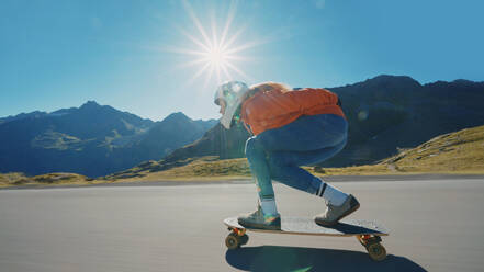 Cinematic downhill longboard session. Young woman skateboarding and making tricks between the curves on a mountain pass. Concept about extreme sports and people - DMDF04490