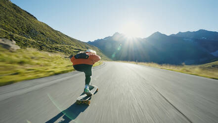 Cinematic downhill longboard session. Young woman skateboarding and making tricks between the curves on a mountain pass. Concept about extreme sports and people - DMDF04496