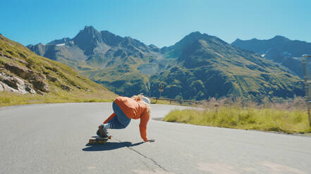 Cinematic downhill longboard session. Young woman skateboarding and making tricks between the curves on a mountain pass. Concept about extreme sports and people - DMDF04504