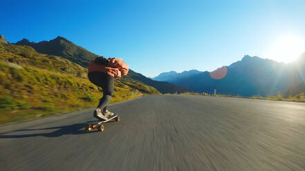 Cinematic downhill longboard session. Young woman skateboarding and making tricks between the curves on a mountain pass. Concept about extreme sports and people - DMDF04518