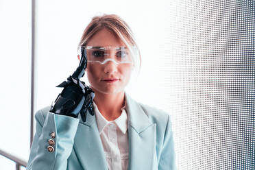 Business woman with cyborg bionic arm and augmented reality visor. Representation of the future that will include human being and tech parts - cyberpunk look - DMDF04558