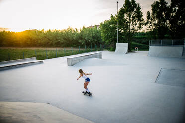 Stylish young woman skating outdoors - Pretty female skater playing with her skate - DMDF04697