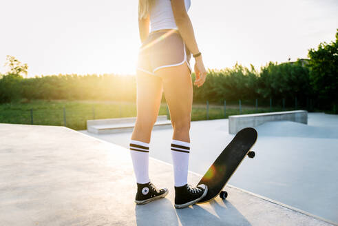 Stylish young woman skating outdoors - Pretty female skater playing with her skate - DMDF04702
