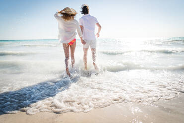 Couple strolling at the beach and smiling - Young adults enjoying summer holidays on a tropical island - DMDF04799