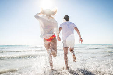 Couple strolling at the beach and smiling - Young adults enjoying summer holidays on a tropical island - DMDF04800