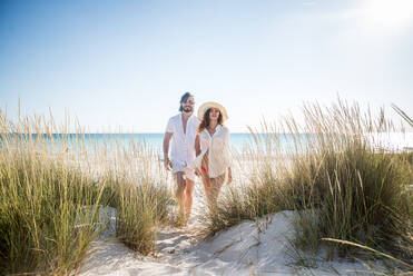 Couple strolling at the beach and smiling - Young adults enjoying summer holidays on a tropical island - DMDF04806