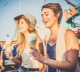 Two young women eating ice cream of Santa Monica pier and having fun - DMDF04844