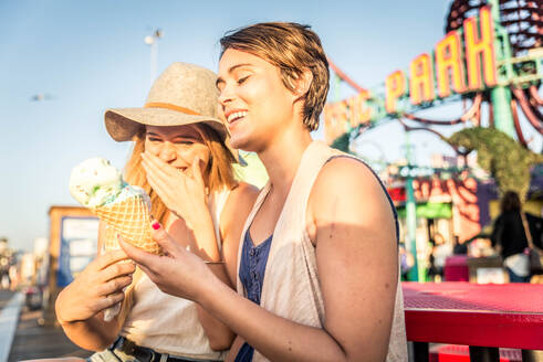 Two young women eating ice cream of Santa Monica pier and having fun - DMDF04845
