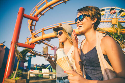 Two young women eating ice cream of Santa Monica pier and having fun - DMDF04848