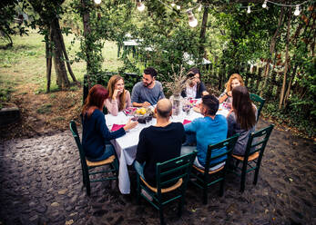 Gruppe von Freunden in einem Restaurant im Freien - Menschen beim Abendessen in einem Hausgarten - DMDF04858