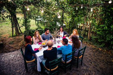 Gruppe von Freunden in einem Restaurant im Freien - Menschen beim Abendessen in einem Hausgarten - DMDF04859