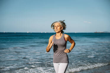 Ältere Frau joggt am Strand - GDBF00077