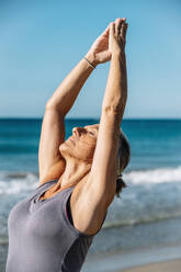 Frau mit geschlossenen Augen beim Yoga am Strand - GDBF00083