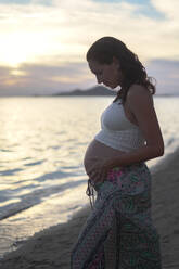 Schwangere Frau berührt Bauch am Strand - DMHF00152