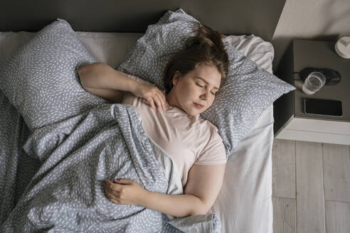 Junge Frau schläft auf dem Bett zu Hause - YBF00215