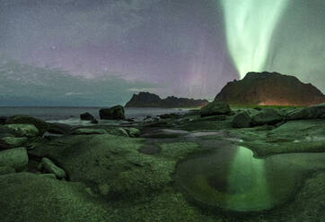 Green lights of Aurora Borealis (Northern Lights) glowing over mountains and Uttakleiv beach, Vestvagoy, Lofoten Islands, Nordland, Norway, Scandinavia, Europe - RHPLF27354