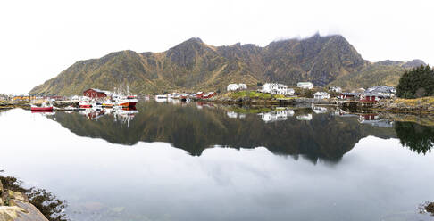 Fishing village of Ballstad and mountains mirrored in the calm waters of a fjord, Vestvagoy, Lofoten Islands, Nordland, Norway, Scandinavia, Europe - RHPLF27591