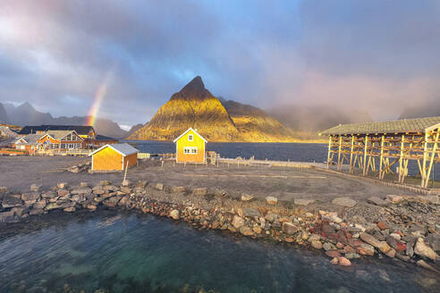 Aerial panoramic view of traditional rorbu and Olstind peak under the rainbow, Sakrisoy, Reine, Lofoten Islands, Nordland, Norway, Scandinavia, Europe - RHPLF27606