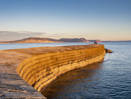 People at the end of The Cobb enjoying the evening light, Lyme Regis, Dorset, England, United Kingdom, Europe - RHPLF27774