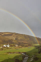 A valley rainbow forms in the face of an autumn squall, in Duckpool, a remote cove near Bude, north coast of Cornwall, England, United Kingdom, Europe - RHPLF27920