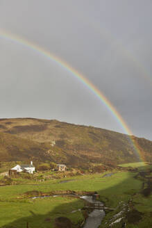 A valley rainbow forms in the face of an autumn squall, in Duckpool, a remote cove near Bude, north coast of Cornwall, England, United Kingdom, Europe - RHPLF27920