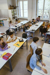 High angle view of male and female students attending lecture sitting in classroom - MASF38309