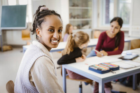 Seitenansicht Porträt einer lächelnden Studentin im Klassenzimmer sitzend - MASF38331