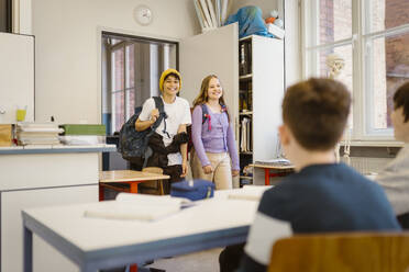 Smiling male and female students entering in classroom - MASF38394