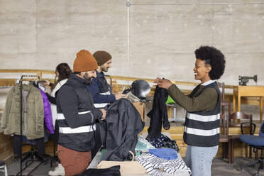 Happy male and female workers sorting recycled clothes at recycling center - MASF38433