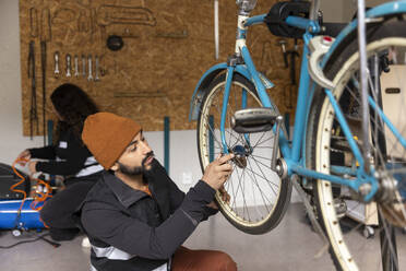 Männlicher Techniker repariert ein Fahrradrad in der Werkstatt eines Recyclingzentrums - MASF38487